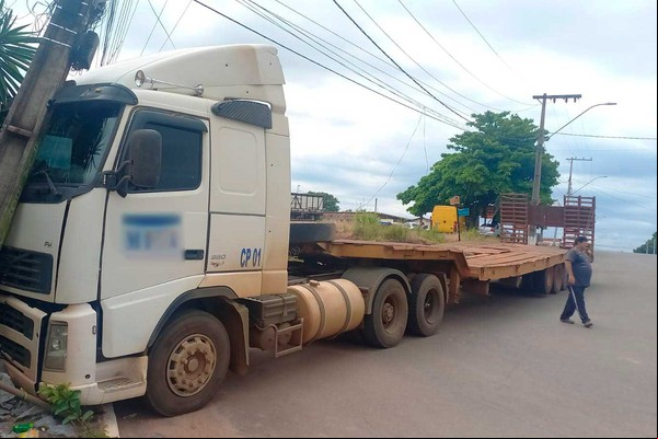 Carreta prancha desgovernada vai parar em poste e deixa estrutura sustentada pela fiação